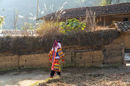 Ha Giang, Vietnam - Nov 26, 2018: Lo Lo ethnic minority woman in traditional costume with old wall-thicked house at Lo Lo Chai village, Dong Van districtのeditorial素材