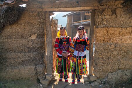 Ha Giang, Vietnam - Nov 26, 2018: Lo Lo ethnic minority woman in traditional costume with old wall-thicked house at Lo Lo Chai village, Dong Van districtのeditorial素材