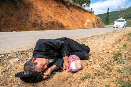 Ha Giang, Vietnam - Nov 25, 2018: Drunk man lying on road side in Dong Van district.のeditorial素材