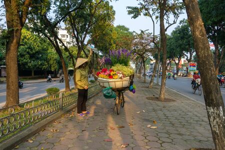Hanoi, Vietnam - Feb 18, 2010: Flower basket on bike of street vendor on Kim Ma street in Hanoi. Yellow leaf trees. Autumn or winter seasonのeditorial素材