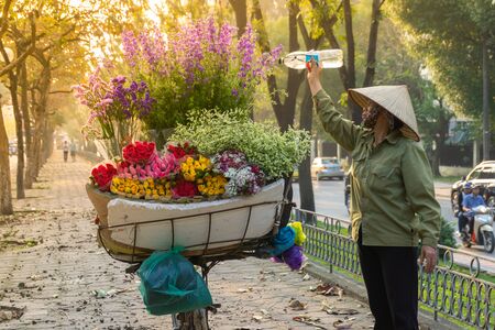Hanoi, Vietnam - Feb 18, 2010: Flower basket on bike of street vendor on Kim Ma street in Hanoi. Yellow leaf trees. Autumn or winter seasonのeditorial素材
