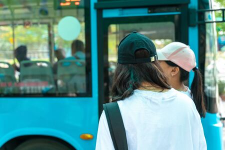 Asian young girl wear hat waiting for bus at bus stopの写真素材