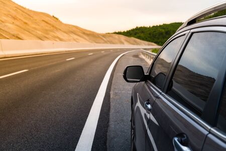 Car parked on highway side with curved road and mountain backgroundの写真素材