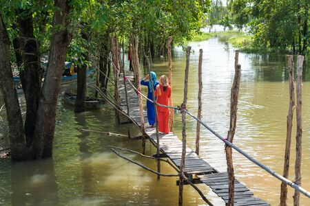 Wooden bridge in floating water season in Mekong delta, southern Vietnam, with Muslim girls walking on the bridgeの写真素材