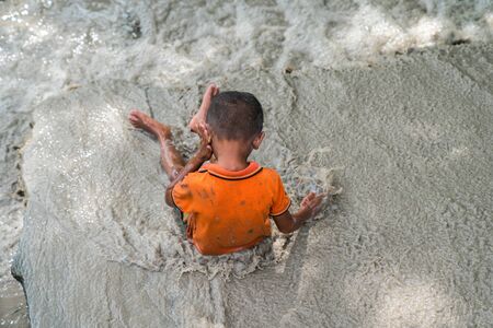 Young boy child playing in the mud puddle on a summer dayの写真素材