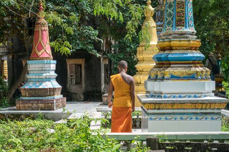 Architecture of an ancient Buddhist temple in Southern Vietnam. Novice monk walking on the groundの写真素材