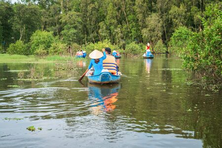 Tourism rowing boat in cajuput forest in floating water season in Mekong delta, Vietnamの写真素材