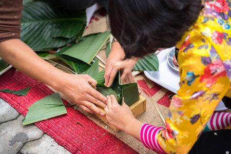 The daughter learning to make Chung cake by hands with his father closeup, Chung cake is the most important traditional Vietnamese lunar New Year (Tet) food.の写真素材
