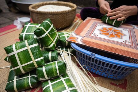 Packaged Chung cakes with female craftsman hands on background. Traditional Vietnamese New Year Tet food.の写真素材