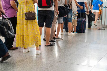 Queue of Asian people waiting at boarding gate at airport. Close-up composition