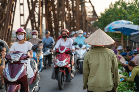 Vietnamese woman with traditional cone hat walking on Long Bien bridge busy streetのeditorial素材