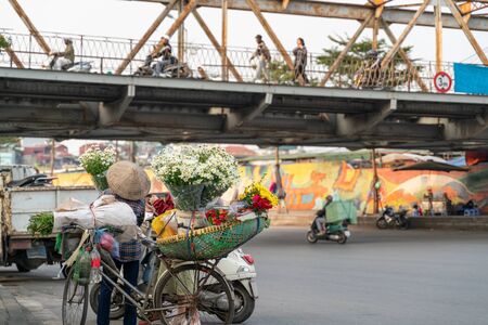 Flower vendor on Hanoi street at early morning with Long Bien old metal bridge on backgroundの写真素材