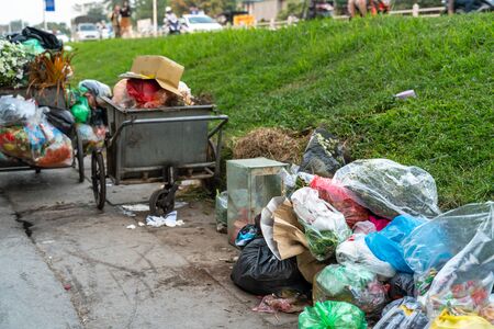 Pile of garbage bags and messy trash on street sidewalk with traffic on background in Hanoi, Vietnamの写真素材
