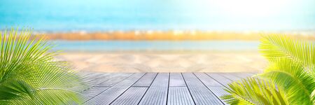 Tropical sea beach with sand, ocean, palm leaves and blue skyの写真素材