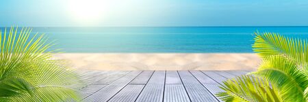 Tropical sea beach with sand, ocean, palm leaves and blue skyの写真素材