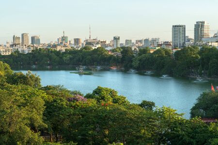 Hoan Kiem lake or Sword lake, Ho Guom in Hanoi, Vietnam with Turtle Tower, green trees and buildings on horizonの写真素材