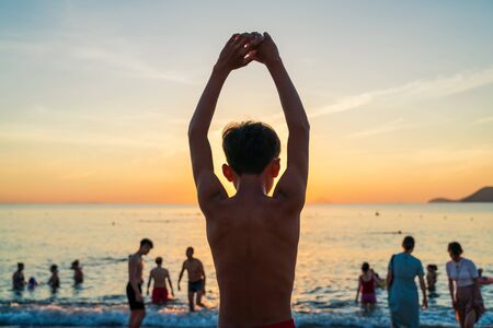 Young Asian boy do exercise on beach during sunrise in summerの写真素材