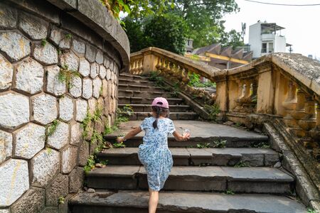 Old open outer stone staircase, aged footpath in Hanoi city with a child running up on stepsの写真素材