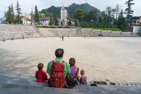 Family members sitting on square in Sapa on vacation in Vietnam. Backpack travel. Large family member.の写真素材