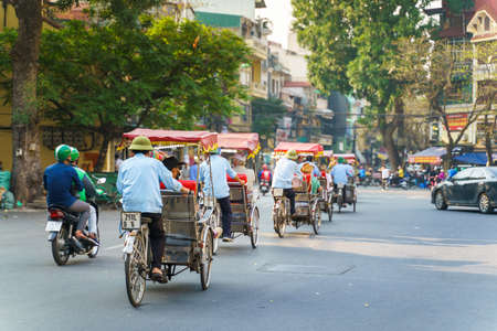 Cyclo driver taking tourist visiting old quarter on street in Hanoi