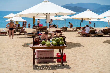 Coconut on the table on the beach in Nha Trang, Vietnam. Tourists enjoying the sun on backgroundの写真素材