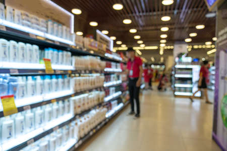 Abstract blurred supermarket aisle with colorful shelves and unrecognizable customers as backgroundの写真素材