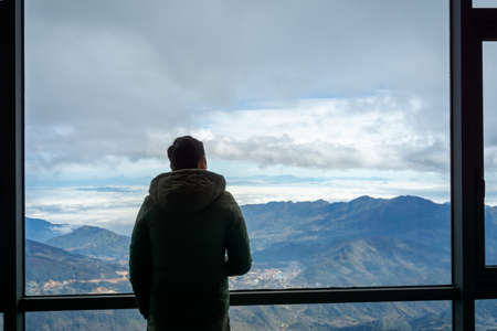 Man travelller overlooking the mountain view from hotel windowの写真素材
