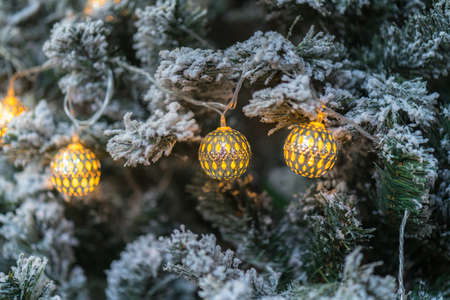 Decorated and illuminated christmas tree with warm toned ball and cold toned pine branchesの写真素材