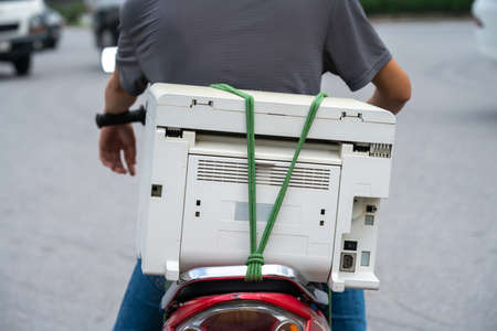 Used printer behind a man on motorbike in Hanoi street.