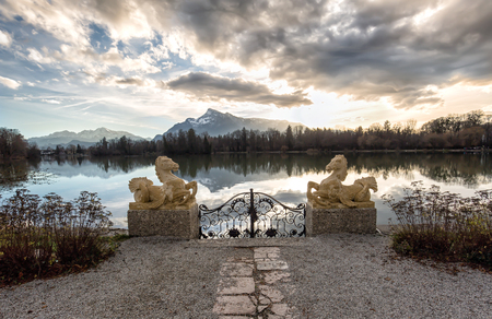 Gate with sculptures at a lake during sunsetの写真素材