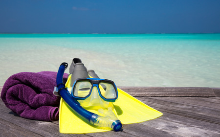 Mask, fins and towel lying on a jettyの写真素材
