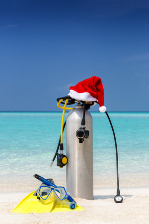 Scuba diving gear with a red Santa hat on a tropical beach with turquoise watersの写真素材