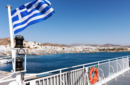 The harbor of Naxos island seen from a ferry boat with a Greek flagの写真素材