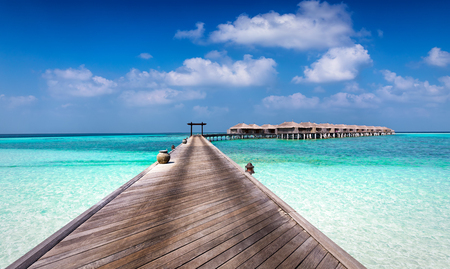 Beautiful classic Maldives background with a wooden boardwalk and bungalowsの写真素材