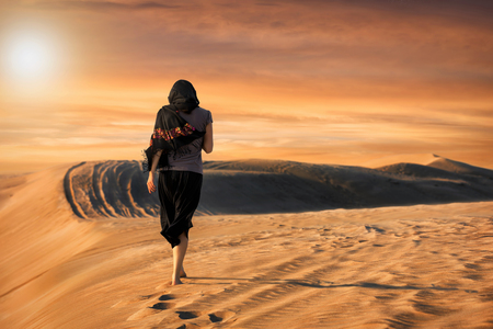 Woman in black walking in the desertの写真素材
