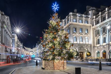 A sparkling, lit christmas tree in the center of London, United Kingdom, during winter might time with blurred street trafficの写真素材