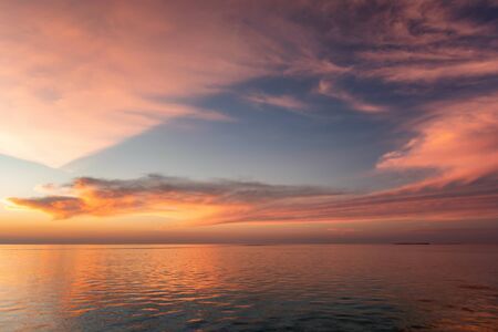 A colorful tropical sunset sky with soft blue, red and oranges tones over the sea