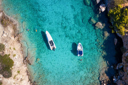 Aerial view of moored rib boats with snorkelers and swimmers at the turquoise colored coast of the...