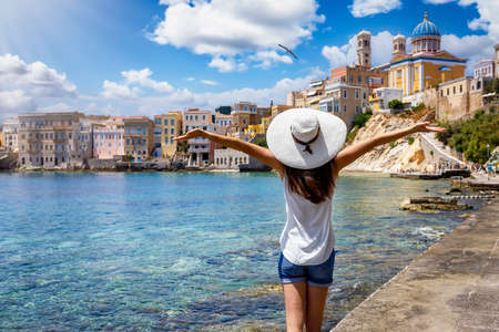 A happy tourist woman looks at the famous Vaporia district at Ermoupoli, Syros island, Cyclades, Greece, during her summer holidaysの写真素材