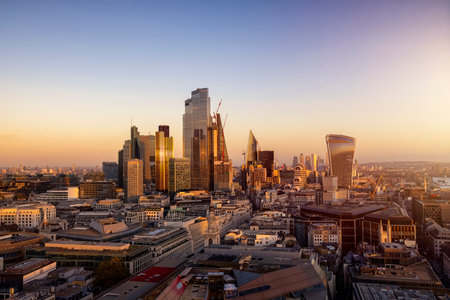 The urban skyline of the City of London during a golden sunset with the completed office skyscrapers reflecting the soft sunlightの写真素材