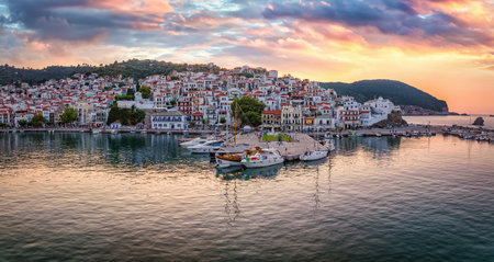 Beautiful, panoramic view of the city and harbour of Skopelos island, Sporades, Greece, during a golden summer sunsetの写真素材