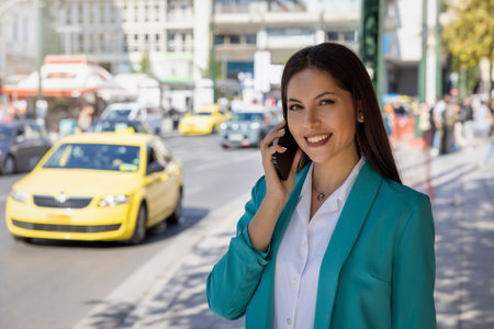 A young, professional, Greek woman in corporate outfit stands in the city center of Athens, Greece, and talks on her telephoneの写真素材