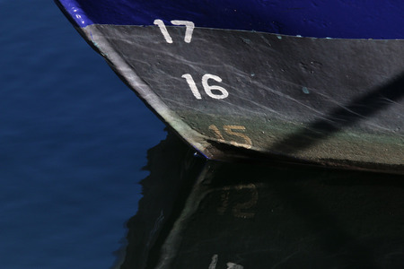 The bow of a fishingboat reflecting in the waterの写真素材