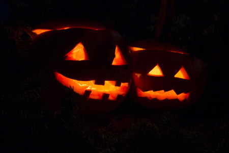 Two halloween pumpins glowing in the darkの写真素材