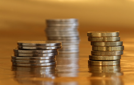 Pile of coins in gold and silver in front of a golden background