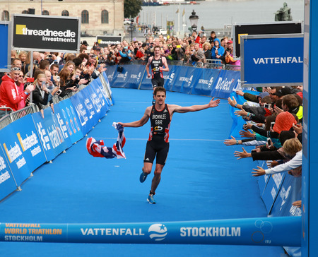 STOCKHOLM - AUG 23, 2014: Jonathan Brownlee waving a flag in the finish of the race only a few yards before his brother in the Men's ITU World Triathlon series event August 23, 2014 in Stockholm, Swedenのeditorial素材