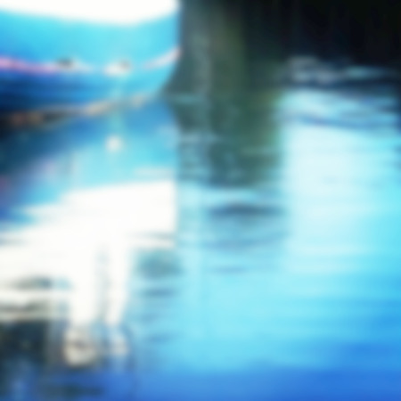 Defocused blue boat reflecting in blue waterの写真素材