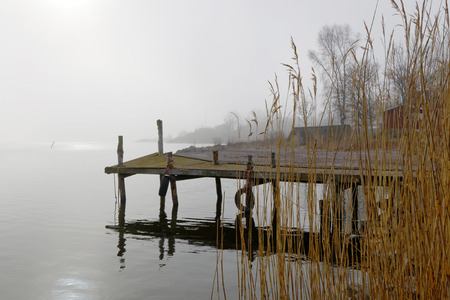 Silhouette of an old wooden bridge a foggy morning and flag in the foregroundの写真素材