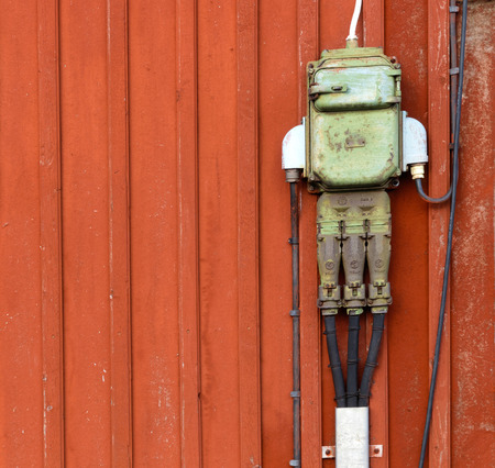 Retro style of electric circuits, sockets and junction boxes mounted on a red wooden wallの写真素材