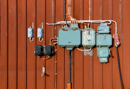 Retro style of electric circuits, sockets and junction boxes mounted on a red wooden wallの写真素材